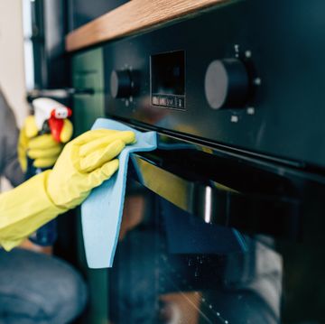 woman cleaning oven in yellow rubber gloves