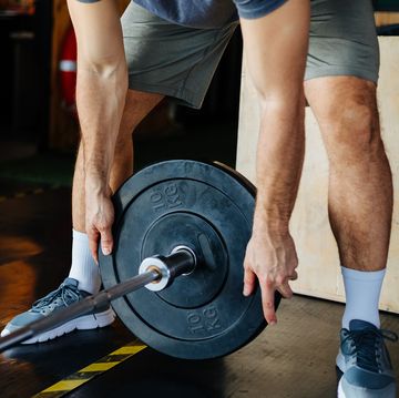 man putting weight on barbell bar man putting weight on barbell bar