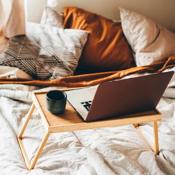 laptop and mug on wooden tray in bed