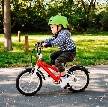 young child riding red bike with green helmet