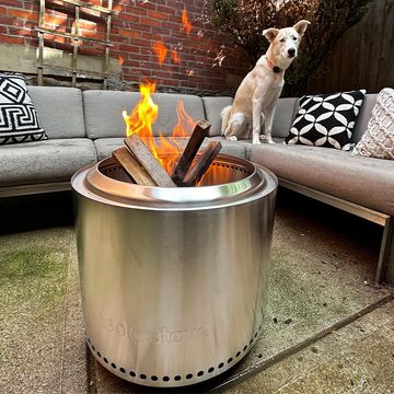 a firepit on an outdoor patio with a couch behind it, and a stone outdoor firepit