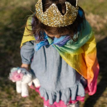 three year old girl with crown and rainbow cape on carrying unicorn toy three year old girl with crown and rainbow cape on carrying unicorn toy
