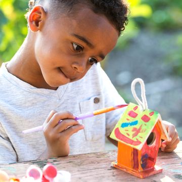 boy painting bird house