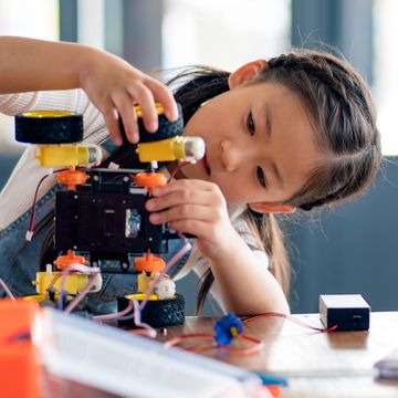 young girl adding wheel to robot young girl adding wheel to robot