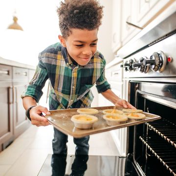 adolescent boy putting mini pies in the oven