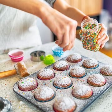 baker adding sprinkles to cupcakes