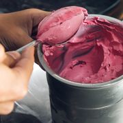 scooping homemade raspberry ice cream out of stainless steel bowl scooping homemade raspberry ice cream out of stainless steel bowl