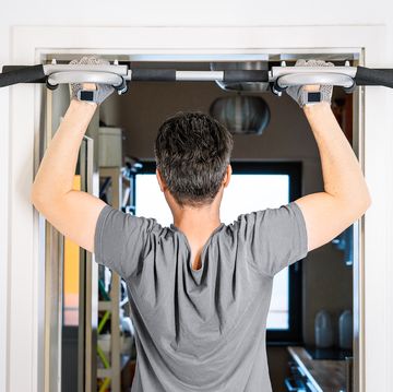 man using pull up bar mounted on door in home man using pull up bar mounted on door in home