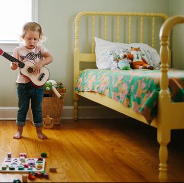 toddler playing guitar in bedroom with two yellow beds toddler playing guitar in bedroom with two yellow beds