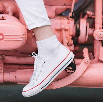woman in white sneakers on pink painted motorcycle woman in white sneakers on pink painted motorcycle