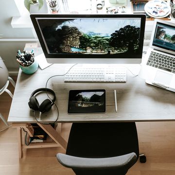 work from home desk with monitor laptop headphones and digital camera